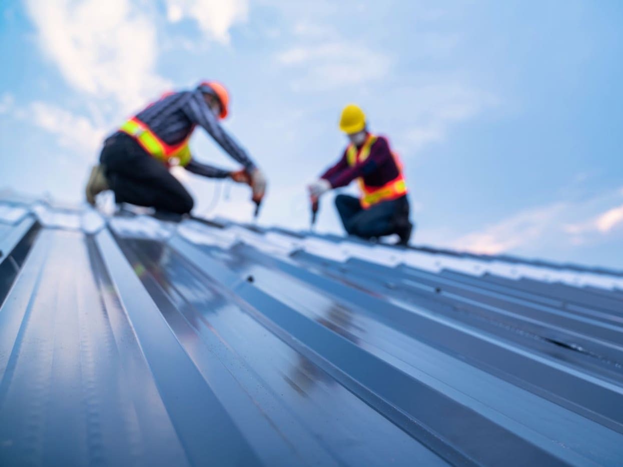 A crew replacing the shingles on a pitched roof